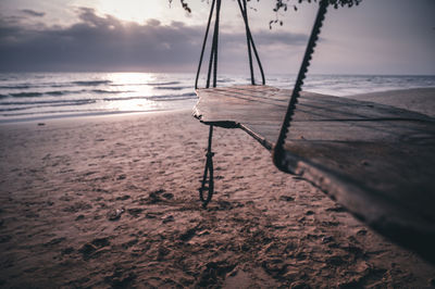 A lonley swing over a empty beach during sunset