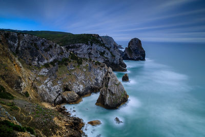 Rock formations in sea against blue sky