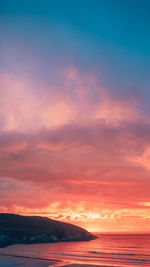 Scenic view of sea against dramatic sky during sunset