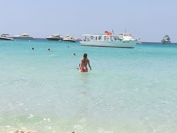 People sitting on sea shore against sky