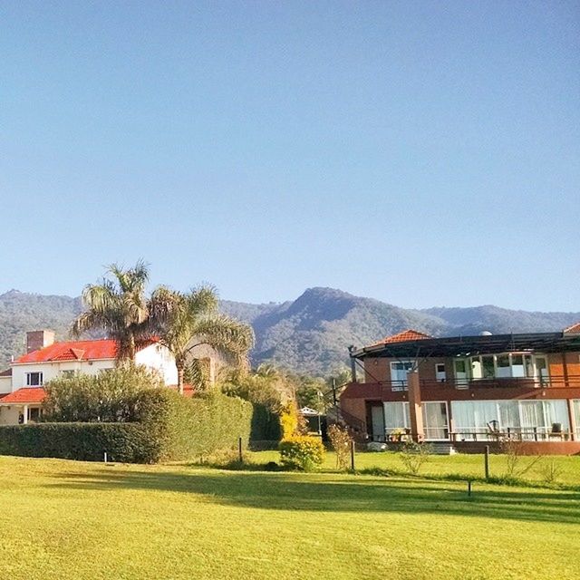 clear sky, building exterior, architecture, built structure, copy space, house, mountain, blue, tree, landscape, residential structure, residential building, village, nature, field, grass, beauty in nature, tranquil scene, day, tranquility