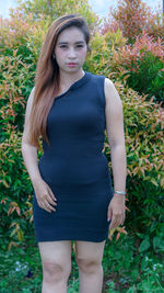 Portrait of teenage girl standing against plants