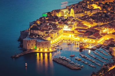 High angle view of illuminated buildings by sea at night