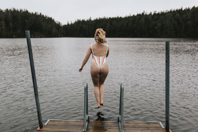 Rear view of woman jumping into lake