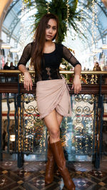 Portrait of female model standing against railing in building