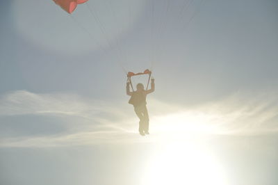 Silhouette person paragliding against sky during sunset