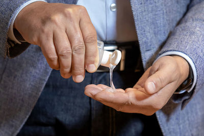 Man using wash hand sanitizer gel dispenser adopting to prevent the diffusion of the coronavirus.