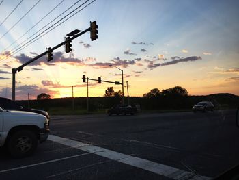 Cars on road against sky during sunset