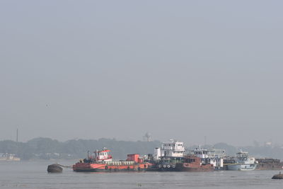 Boats sailing in sea against clear sky