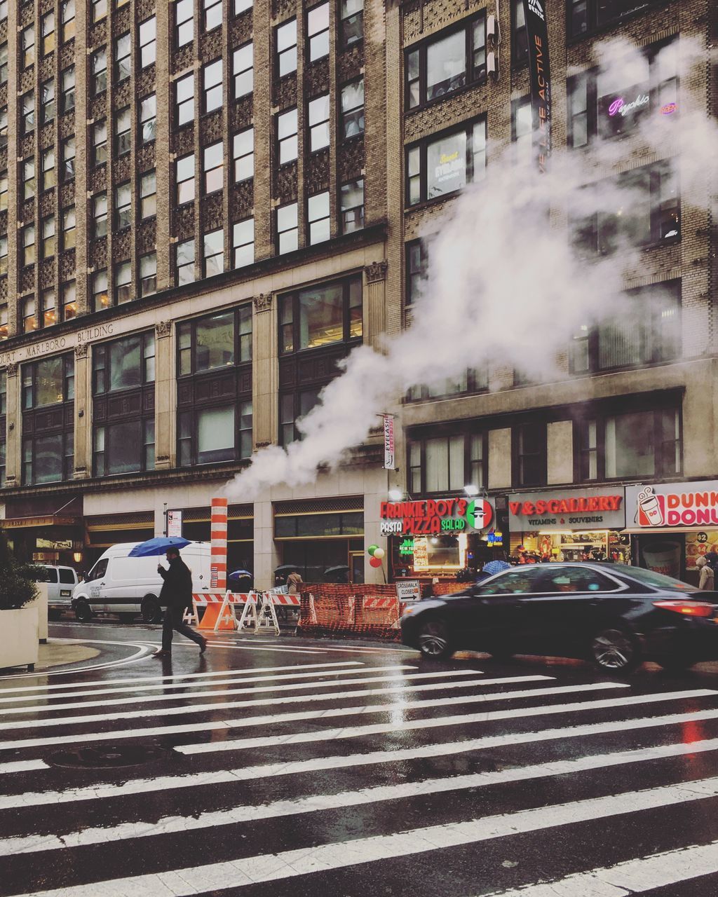 building exterior, city, architecture, built structure, street, crossing, transportation, zebra crossing, crosswalk, road marking, walking, smoke - physical structure, men, motion, road, mode of transportation, real people, city life, marking, day, city street, outdoors, pollution, air pollution