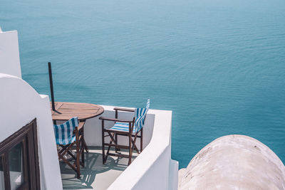High angle view of chairs on table by sea
