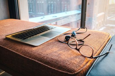 Close-up of laptop by headphones and eyeglasses on sofa