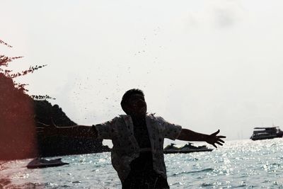 Rear view of man standing by sea against sky