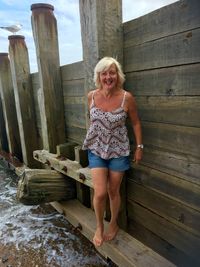 Portrait of smiling woman standing on wood at beach