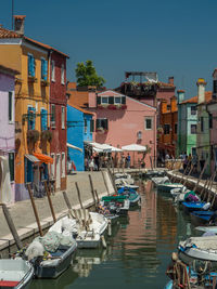 Boats moored at harbor against buildings in city