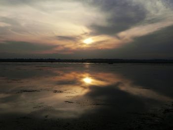 Scenic view of sea against cloudy sky at sunset