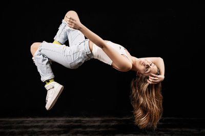 Midsection of woman dancing against black background