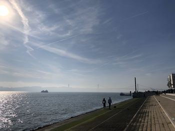 People walking by sea against sky