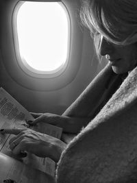 Side view of woman reading magazine in airplane