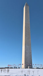 National mall covered with snow, low angle view of washington monument on blue sky