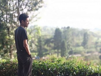 Side view of young man looking away against plants