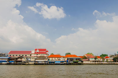Houses by sea against sky