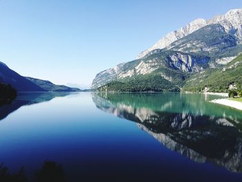 Scenic view of lake and mountains against clear blue sky