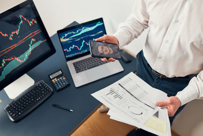 Midsection of businessman using laptop at office