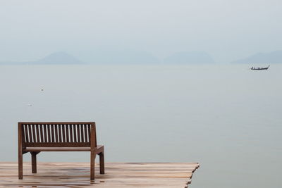 Chair on sea against clear sky