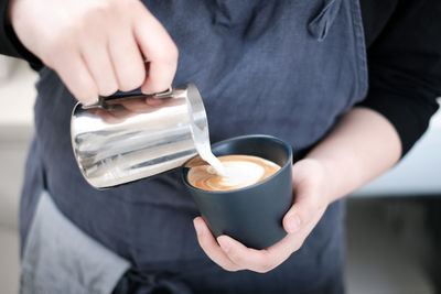 Midsection of man making froth art on coffee