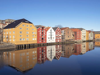 Colourful traditional old houses reflected in the river nidelva in trondheim, norway