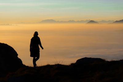 Silhouette man standing on shore against sky during sunset