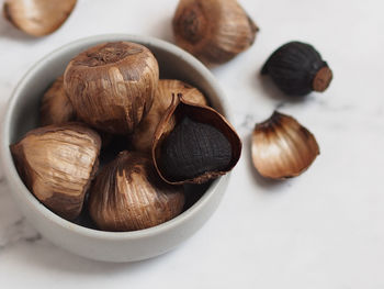 Close-up of roasted coffee beans in bowl on white background