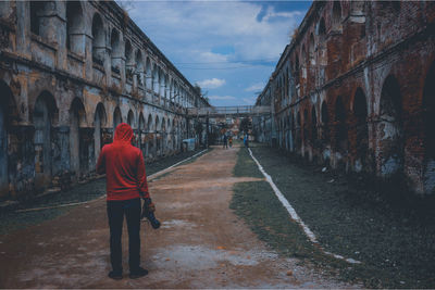 Rear view of man walking on footpath in city