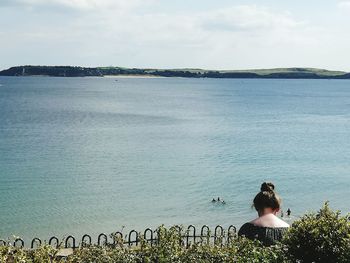 Rear view of woman standing by sea against sky