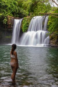 Full length of man splashing water in waterfall