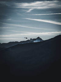 Silhouette birds flying over mountains against sky