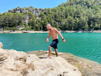 Full length of shirtless man on rock