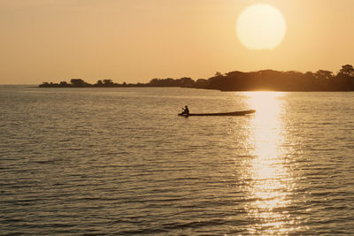 Silhouette person in sea against sky during sunset