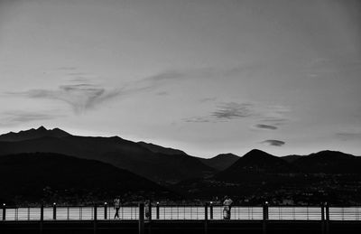 Scenic view of lake by silhouette mountains against sky