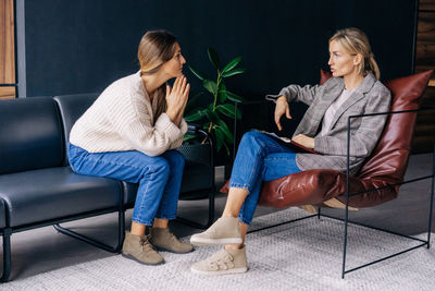 Sad female client listens carefully to the advice of a professional psychologist at a session.