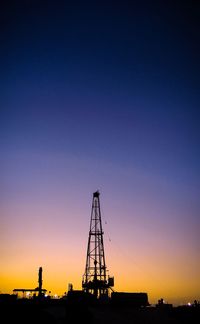 Silhouette of factory against clear sky during sunset