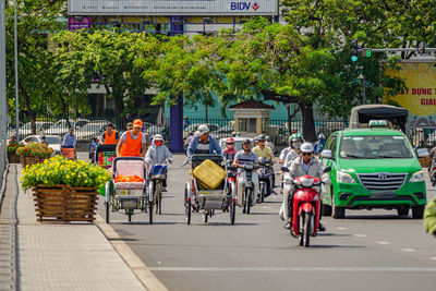 Rear view of people riding motorcycle on city street