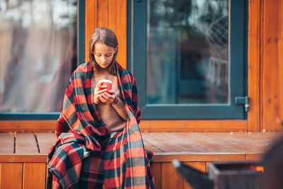Full length of young woman holding coffee cup in cafe