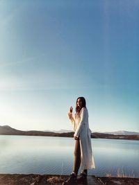 Woman standing on shore against sky