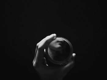 Close-up of hand holding drink against black background