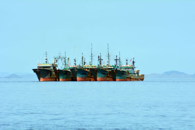 Ships in sea against clear blue sky