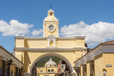 Low angle view of clock tower amidst buildings against sky