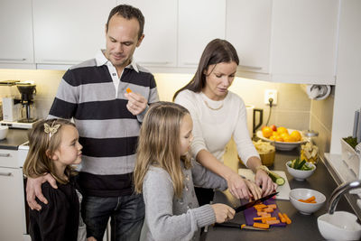 Family cutting vegetables at kitchen counter