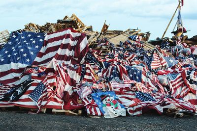 Various flags on beach against sky